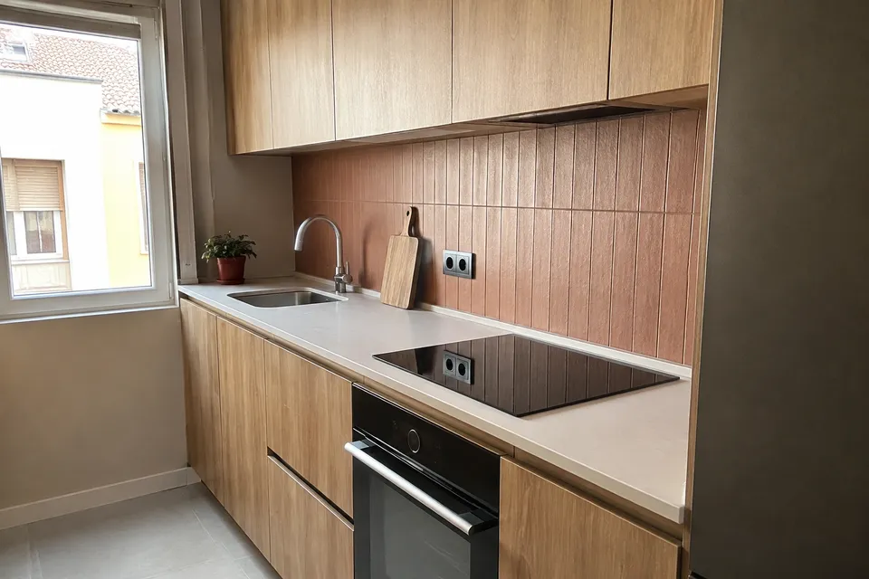 Cocina lineal de madera con encimera clara y azulejos verticales
